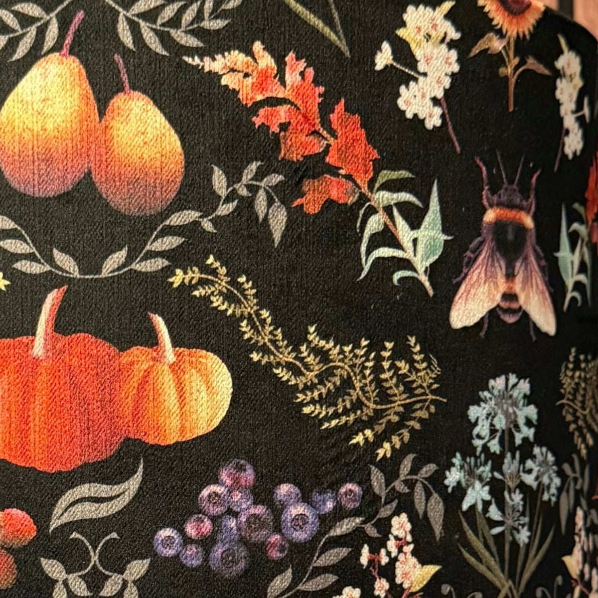 Decorative lamp with a Halloween-themed lampshade featuring pumpkins and foliage against a striped background.
