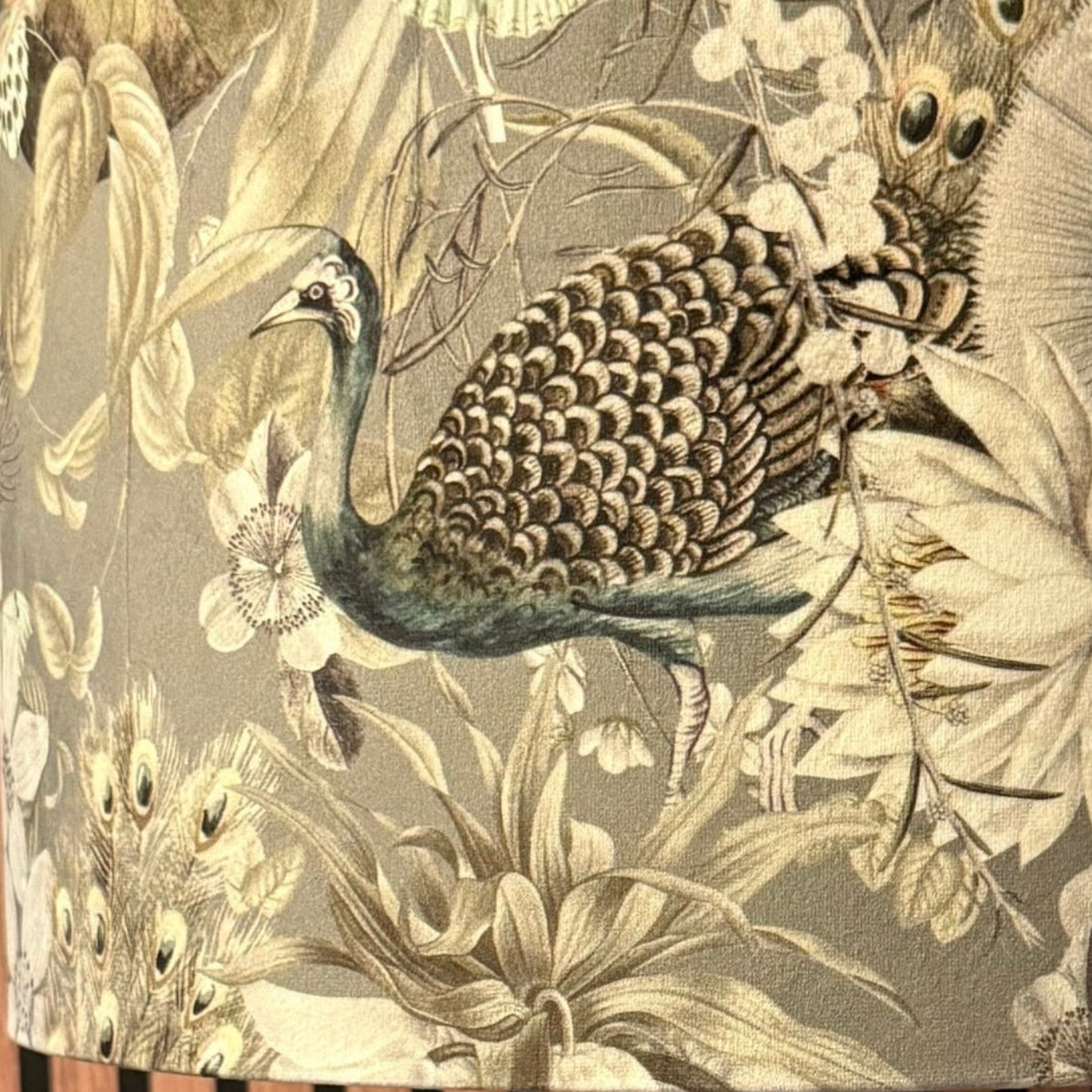Lamp with decorative shade featuring birds and flowers against a wooden slat background