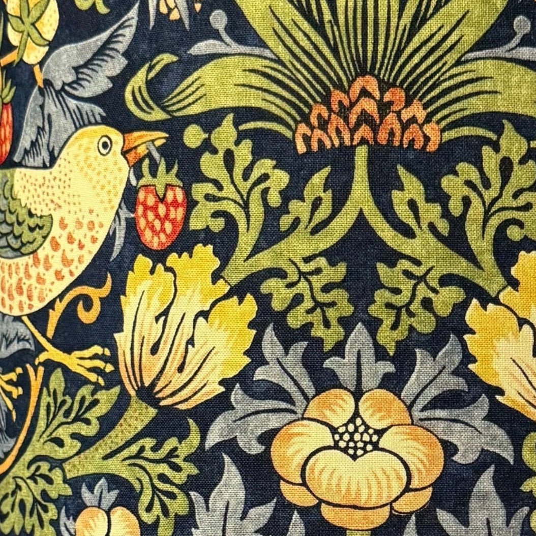 Decorative lamp with a floral and bird patterned shade against a striped wooden background